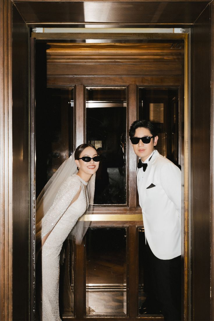 Couple de mariés aux lunettes noires dans un ascenseur en bois